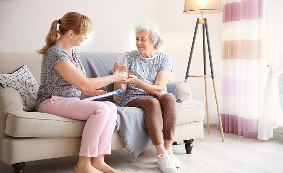 A caregiver giving a glass of water to a senior