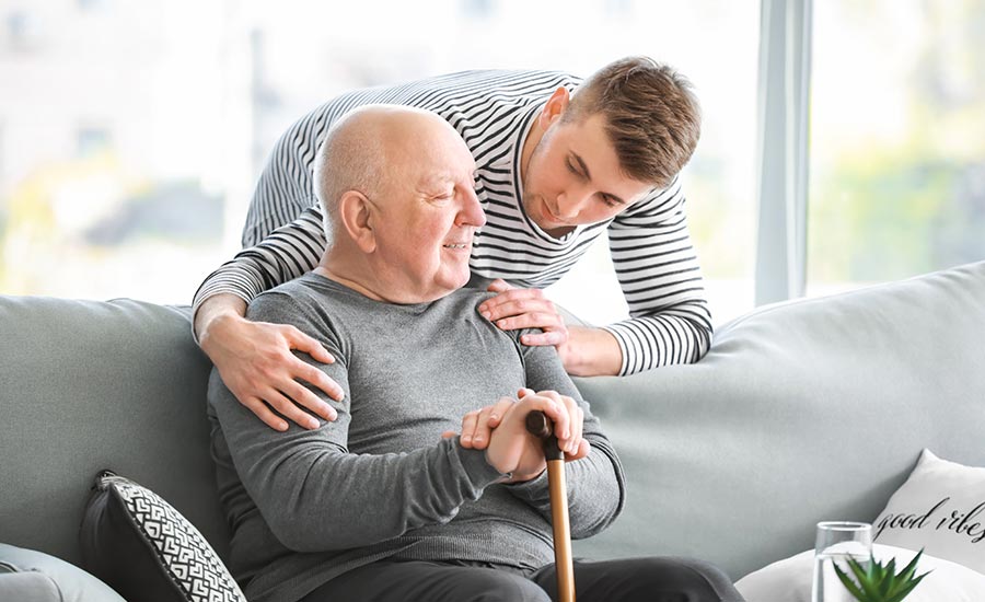A younger male caregiver is taking care of a senior