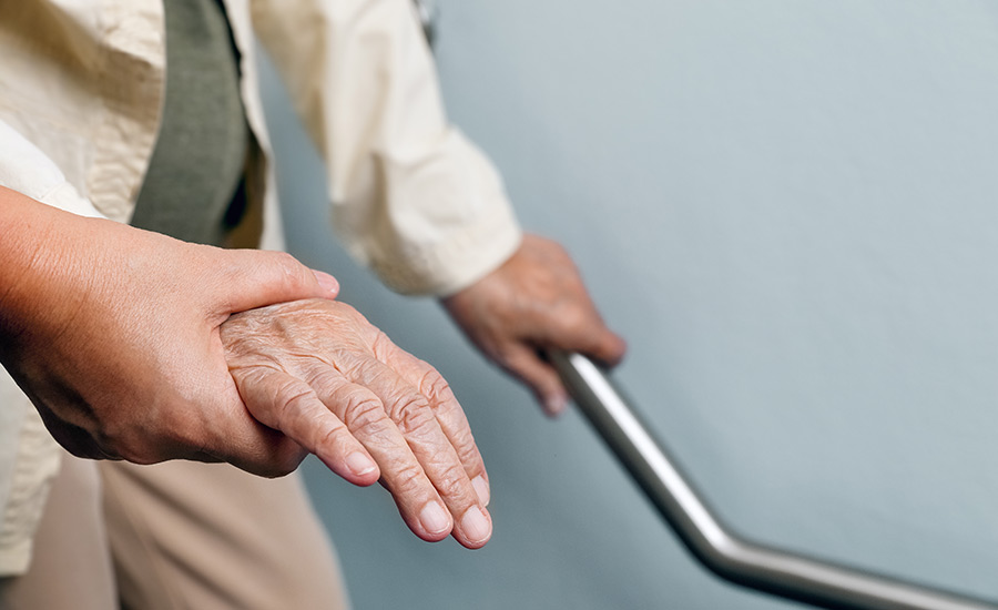 An elderly woman holding a handrail