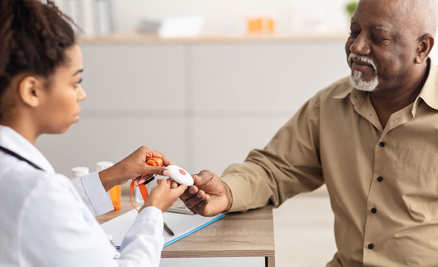 A doctor showing an elderly man a PERS device​