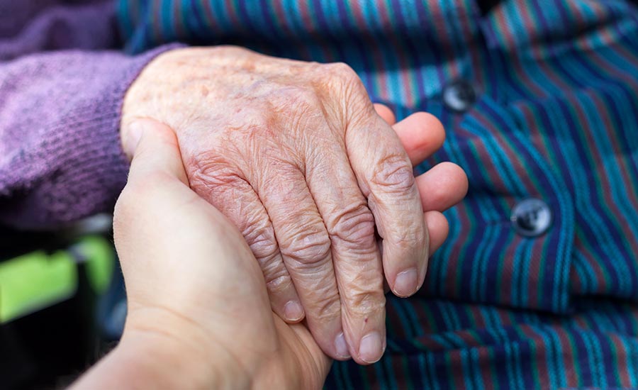 A dementia patient holding a caregiver's hand