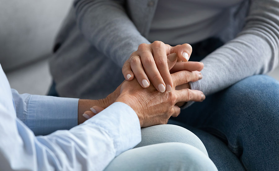 A family caregiver holding a senior female's hands