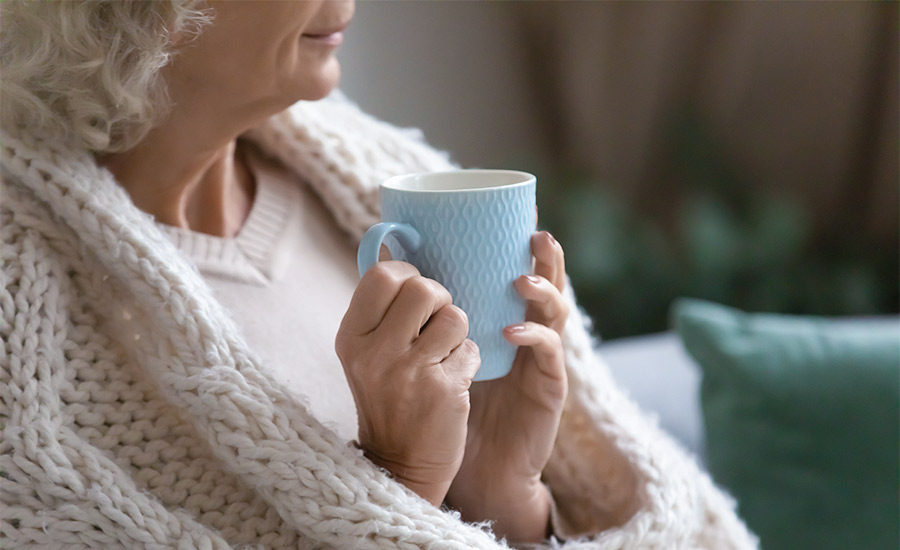 An elderly woman holding a cup of coffee