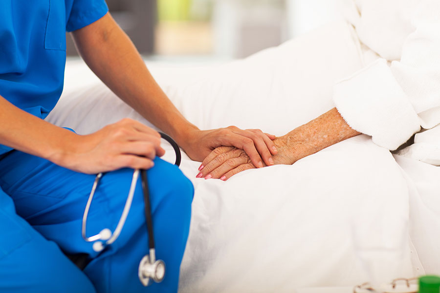 A professional caregiver holding an elderly patient's hand