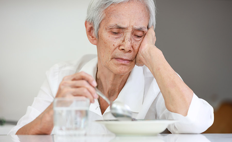 A senior woman trying to eat a meal