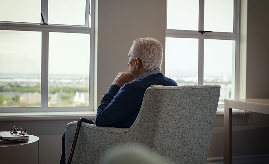 An elderly man looking outside the window​