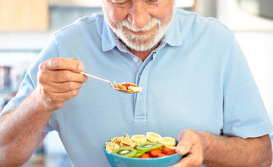 An elderly man eating a healthy bowl of fruits