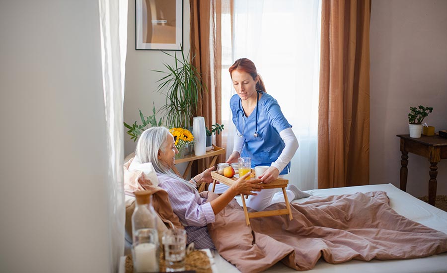 An elderly woman eating breakfast in bed since she’s on bedfast