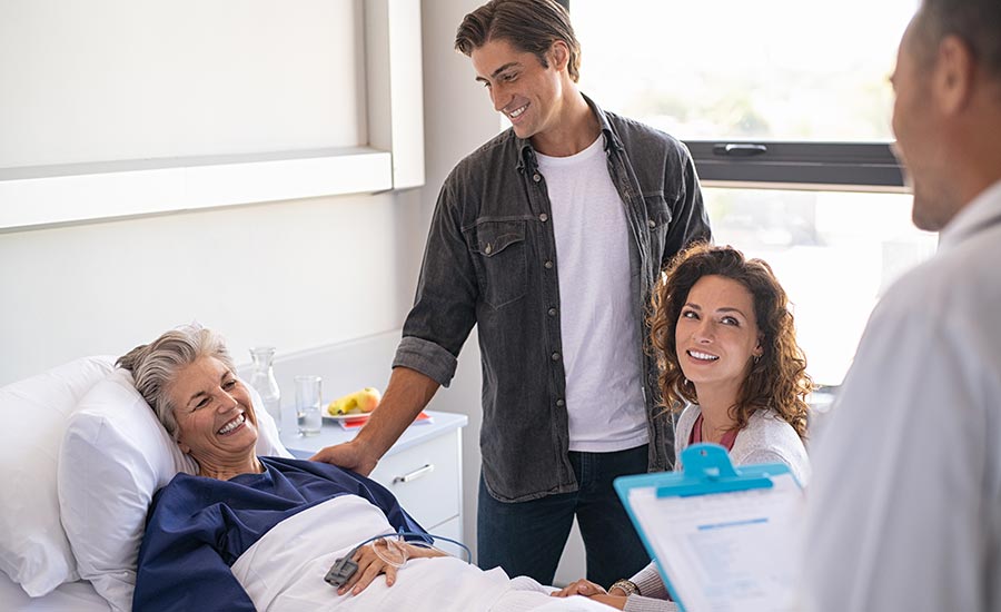An elderly woman smiling at her doctor while being bedfast